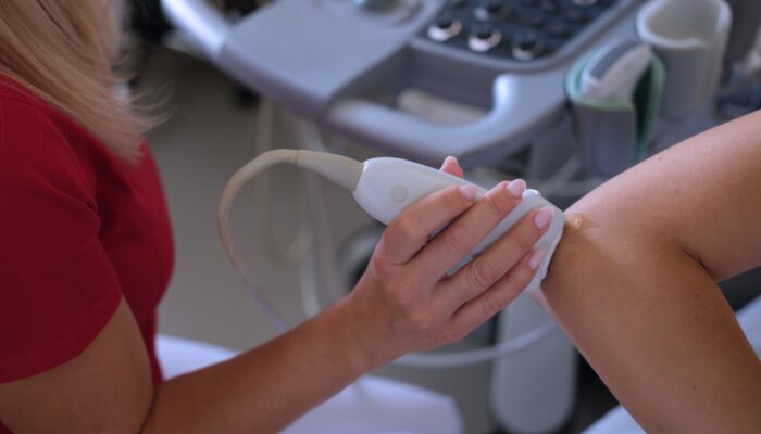 Therapeut behandelt elleboog van patient met een echografie-apparaat